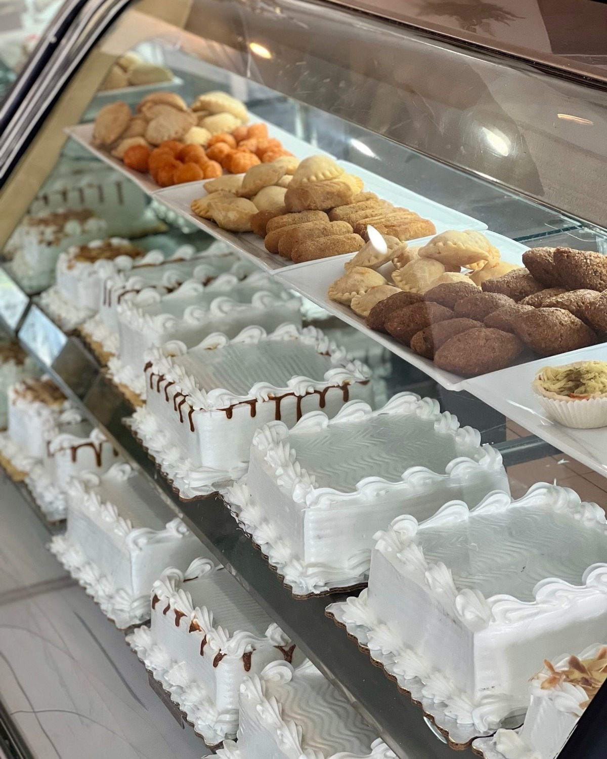 Vitrina de Nené Repostería con bizcochos de crema blanca y bandejas de dulces